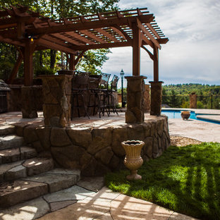 Esempio di un grande patio o portico stile rurale dietro casa con pavimentazioni in pietra naturale e una pergola