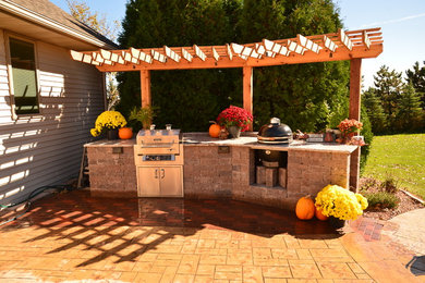 Patio kitchen - large contemporary backyard patio kitchen idea in Milwaukee with a pergola