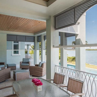 Ispirazione per un grande patio o portico costiero dietro casa con pavimentazioni in pietra naturale e un tetto a sbalzo