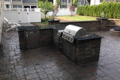 This is an example of a medium sized mediterranean back patio in Boston with an outdoor kitchen, concrete paving and no cover.
