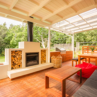 Immagine di un patio o portico contemporaneo con un focolare, pedane e un tetto a sbalzo