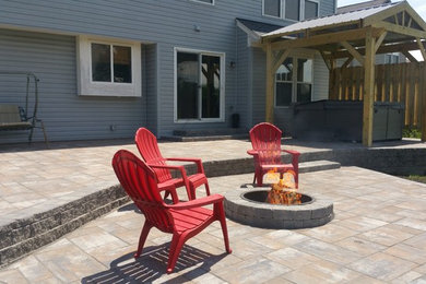Ejemplo de patio tradicional renovado de tamaño medio sin cubierta en patio trasero con brasero y adoquines de hormigón