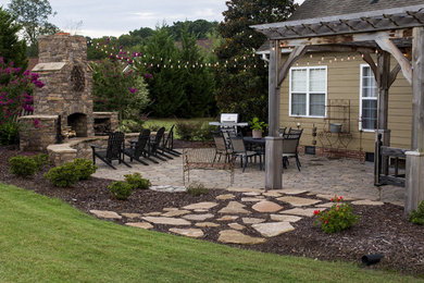 Esempio di un patio o portico chic di medie dimensioni e dietro casa con un focolare, pavimentazioni in pietra naturale e una pergola