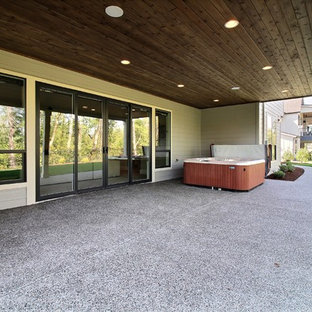 Esempio di un ampio patio o portico american style dietro casa con lastre di cemento e un tetto a sbalzo