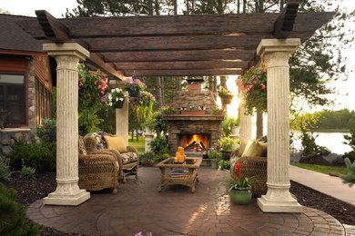 Cette photo montre une terrasse arrière tendance de taille moyenne avec un foyer extérieur, une pergola et des pavés en brique.