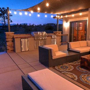 Foto di un grande patio o portico boho chic dietro casa con pavimentazioni in cemento e un parasole