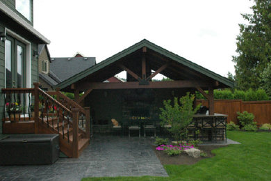 Modelo de patio grande en patio trasero con cocina exterior, adoquines de piedra natural y cenador