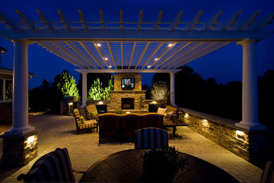 Large elegant backyard stone patio photo in Other with a fire pit and a pergola