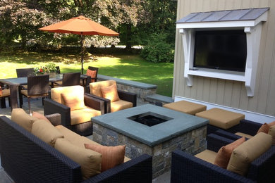 Inspiration for a mid-sized transitional backyard stone patio remodel in New York with a fire pit and no cover