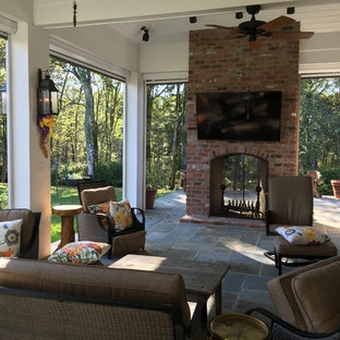 Ispirazione per un patio o portico american style di medie dimensioni e dietro casa con un focolare, piastrelle e un tetto a sbalzo