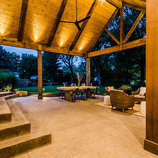 Esempio di un patio o portico stile rurale di medie dimensioni e dietro casa con cemento stampato e un tetto a sbalzo