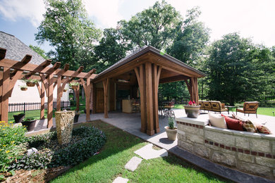 Modelo de patio tradicional grande en patio trasero con cocina exterior, suelo de hormigón estampado y cenador