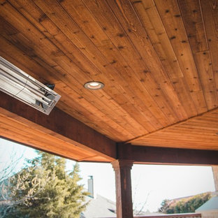 Ispirazione per un patio o portico stile rurale di medie dimensioni e dietro casa con un caminetto, cemento stampato e un tetto a sbalzo