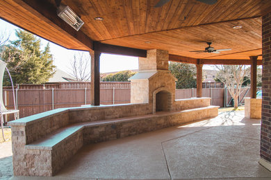 Large mountain style backyard stamped concrete patio photo in Dallas with a fireplace and a roof extension