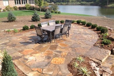 Example of a mid-sized mountain style backyard stone patio design in Chicago with no cover