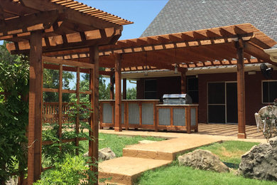 Inspiration for a large rustic backyard stamped concrete patio kitchen remodel in Dallas with a pergola