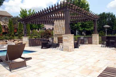 Diseño de patio clásico grande en patio trasero con brasero, adoquines de piedra natural y pérgola