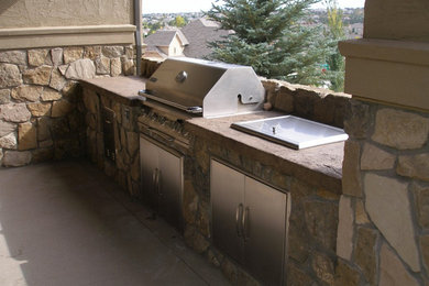 This is an example of a medium sized back patio in Denver with an outdoor kitchen and concrete slabs.