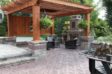 Imagen de patio de estilo americano grande en patio trasero con brasero, adoquines de ladrillo y pérgola