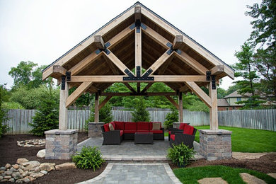 Modelo de patio de estilo americano grande en patio trasero con brasero, adoquines de piedra natural y cenador