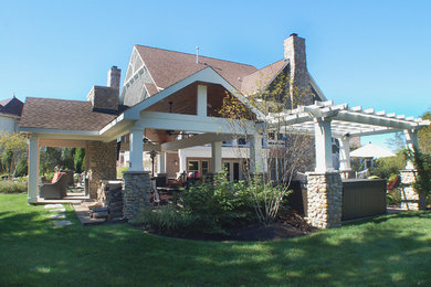 Modelo de patio clásico grande en patio trasero con brasero, losas de hormigón y cenador