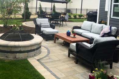 This is an example of a medium sized back patio in Chicago with a fire feature and concrete paving.