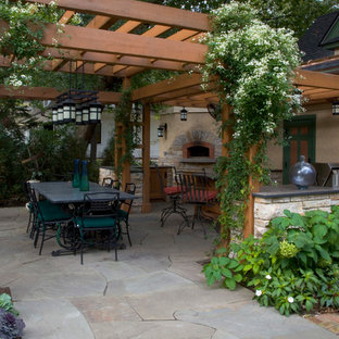 Ispirazione per un patio o portico stile americano di medie dimensioni e dietro casa con pavimentazioni in pietra naturale e una pergola