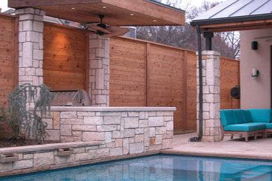 This is an example of a large traditional back patio in Dallas with an outdoor kitchen, natural stone paving and a pergola.