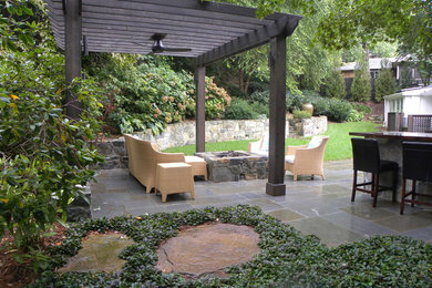 Imagen de patio actual grande en patio trasero con brasero, adoquines de piedra natural y pérgola