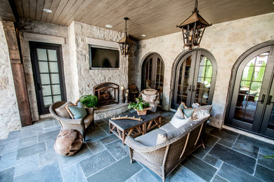 Cette photo montre une terrasse arrière méditerranéenne avec un foyer extérieur, une extension de toiture et des pavés en béton.