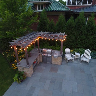 Ispirazione per un ampio patio o portico contemporaneo dietro casa con un focolare, pavimentazioni in pietra naturale e una pergola