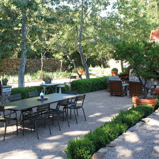 Idee per un patio o portico classico con nessuna copertura, ghiaia e un caminetto