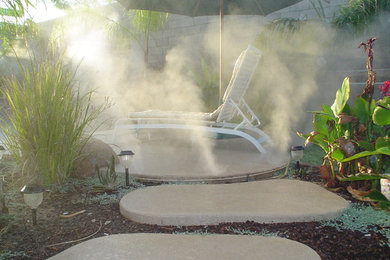 Inspiration for a large tropical backyard concrete paver patio fountain remodel in Phoenix with no cover