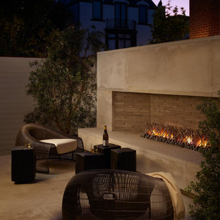 Idee per un grande patio o portico contemporaneo dietro casa con piastrelle, nessuna copertura e un caminetto