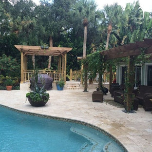 Ispirazione per un patio o portico tropicale dietro casa con pavimentazioni in pietra naturale e una pergola