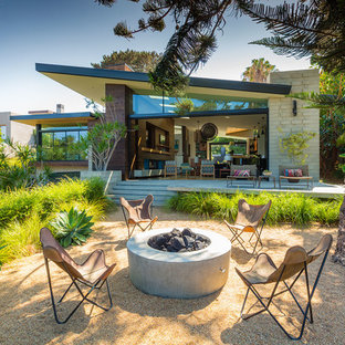 Exemple d'une terrasse arrière rétro avec un foyer extérieur, du gravier et aucune couverture.
