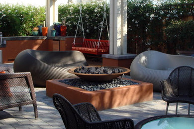 Imagen de patio contemporáneo de tamaño medio en patio trasero con brasero, adoquines de piedra natural y pérgola