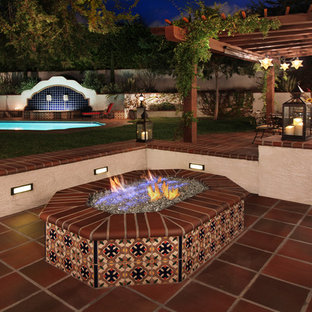 Foto di un grande patio o portico mediterraneo dietro casa con un focolare, piastrelle e una pergola