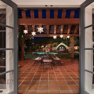 Immagine di un grande patio o portico mediterraneo dietro casa con piastrelle e una pergola