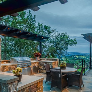Idee per un ampio patio o portico classico nel cortile laterale con pavimentazioni in pietra naturale e una pergola