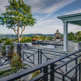 Foto di un ampio patio o portico chic dietro casa con un focolare, pavimentazioni in pietra naturale e un gazebo o capanno