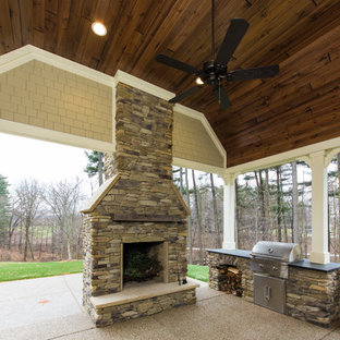 Immagine di un grande patio o portico stile americano dietro casa con un focolare, graniglia di granito e un tetto a sbalzo