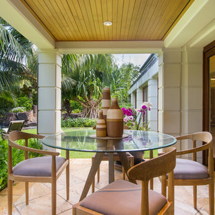 Foto di un piccolo patio o portico tropicale dietro casa con piastrelle e un tetto a sbalzo