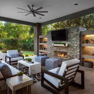 Idee per un grande patio o portico design dietro casa con piastrelle, un tetto a sbalzo e un caminetto