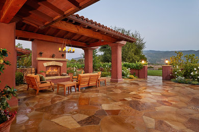 Patio - mid-sized mediterranean backyard stone patio idea in Santa Barbara with a fire pit and a roof extension