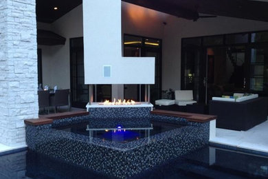 Design ideas for a large modern back patio in Houston with a fire feature, concrete slabs and a roof extension.