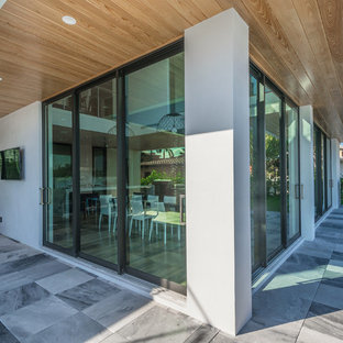 Ispirazione per un patio o portico minimal di medie dimensioni e dietro casa con piastrelle e un tetto a sbalzo