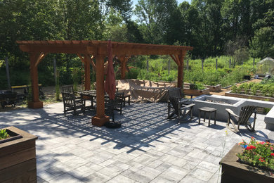 Example of a large backyard concrete paver patio design in Portland Maine with a pergola and a fire pit