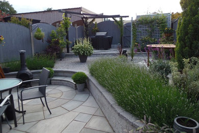 Imagen de patio actual pequeño en patio trasero con adoquines de piedra natural y pérgola