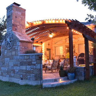 Immagine di un patio o portico american style dietro casa e di medie dimensioni con pavimentazioni in pietra naturale e una pergola